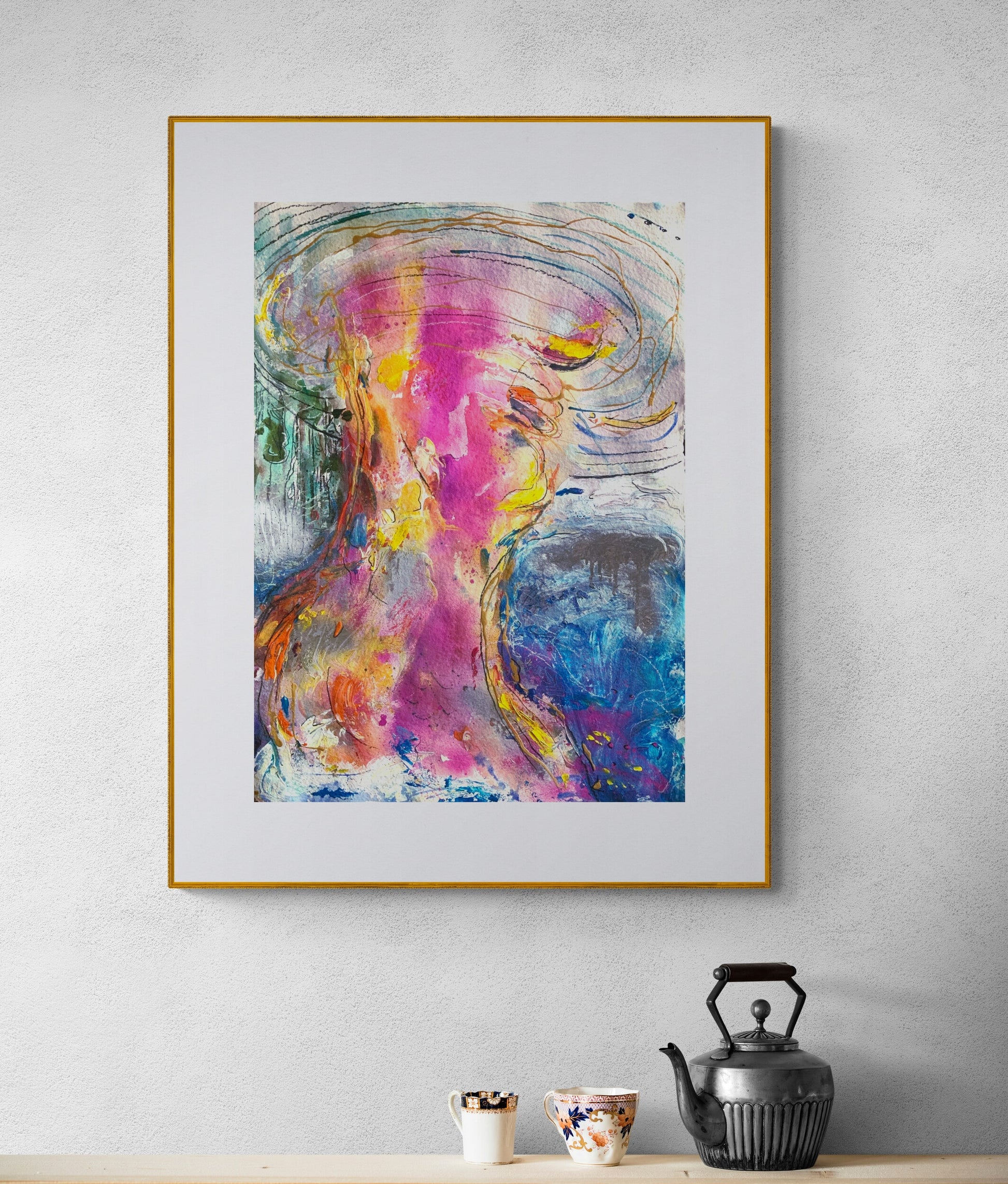 Framed abstract painting on a wall with a teapot and cups below.