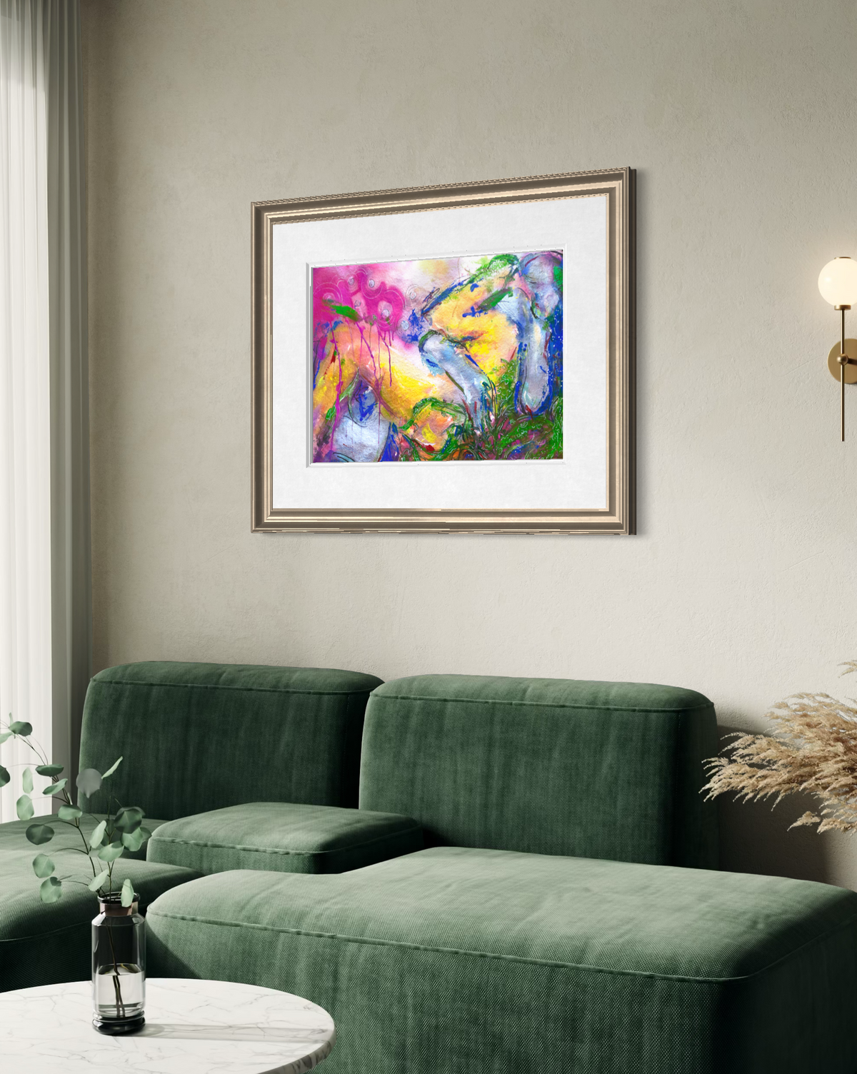 A framed abstract painting with vibrant yellow, pink, blue, and green brushstrokes, displayed on a beige wall above a green sofa in a modern living room setting.