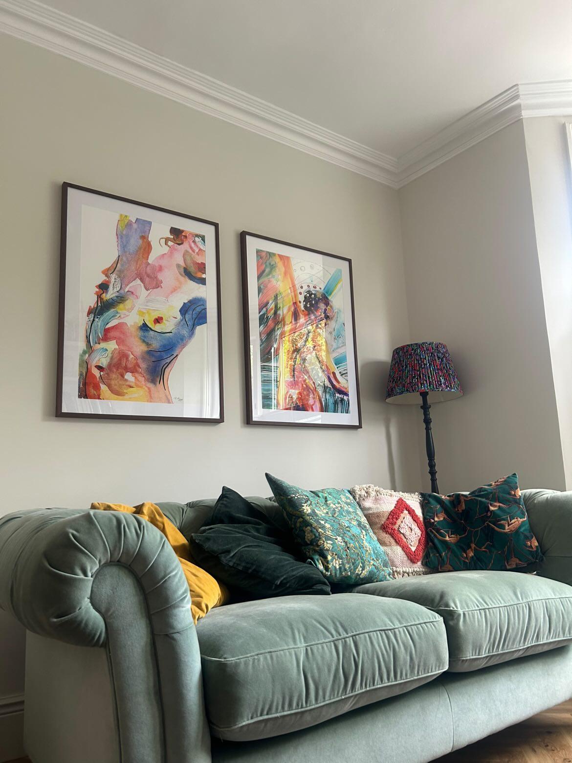 Living room with a light gray sofa, colorful pillows, and two framed artworks on the wall.