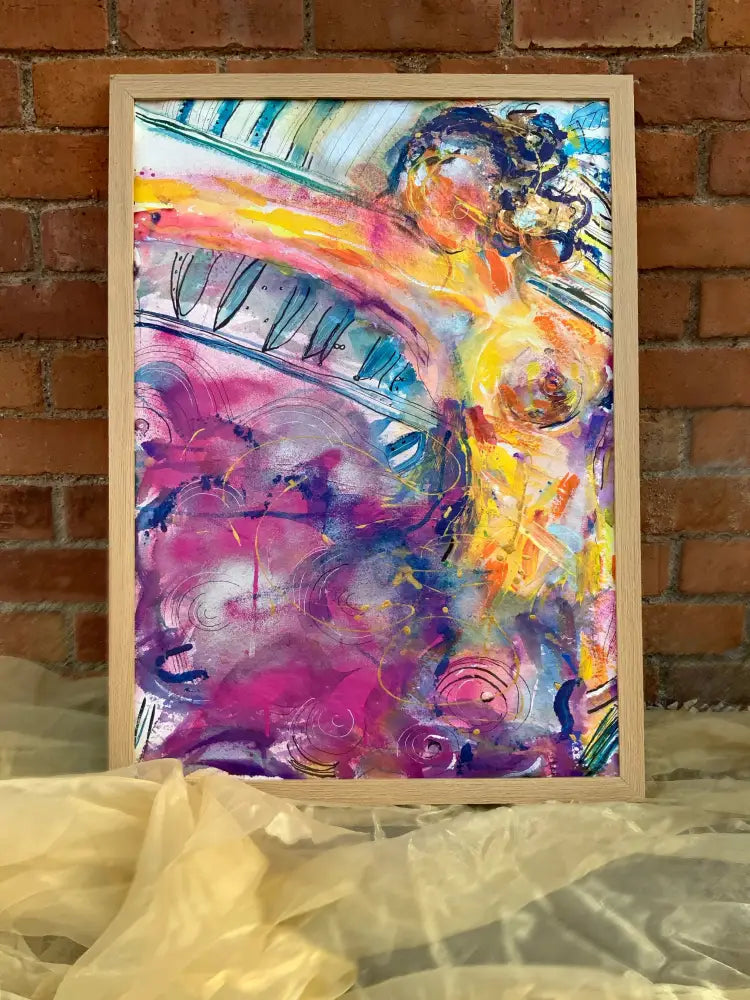 Colorful abstract painting in a wooden frame on a textured surface with a brick wall background.