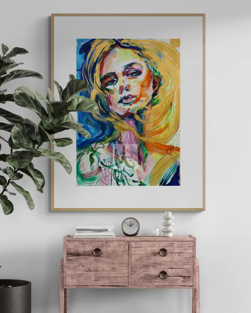 Framed abstract art of a woman's face on a wall above a wooden console table with decorative items.